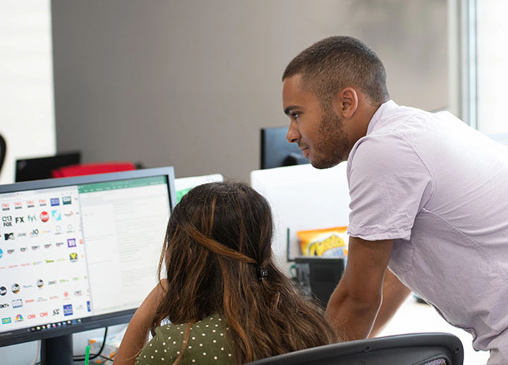 A faculty member looking over a student's shoulder as they work on a computer