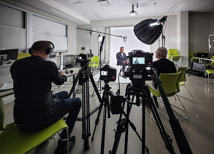 A scene that is being recorded  where you see the cameraman and an interviewer